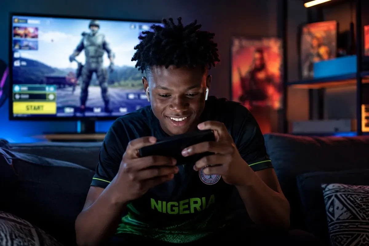 A young person playing a mobile game on a smartphone in an African city